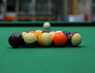 Jugendclub TwentyTwo Berlin Billard Zu sehen sind die Billardkugeln in ihrer dreieckigen Starterposition. Sie leigen auf einem grünen Billardtisch.